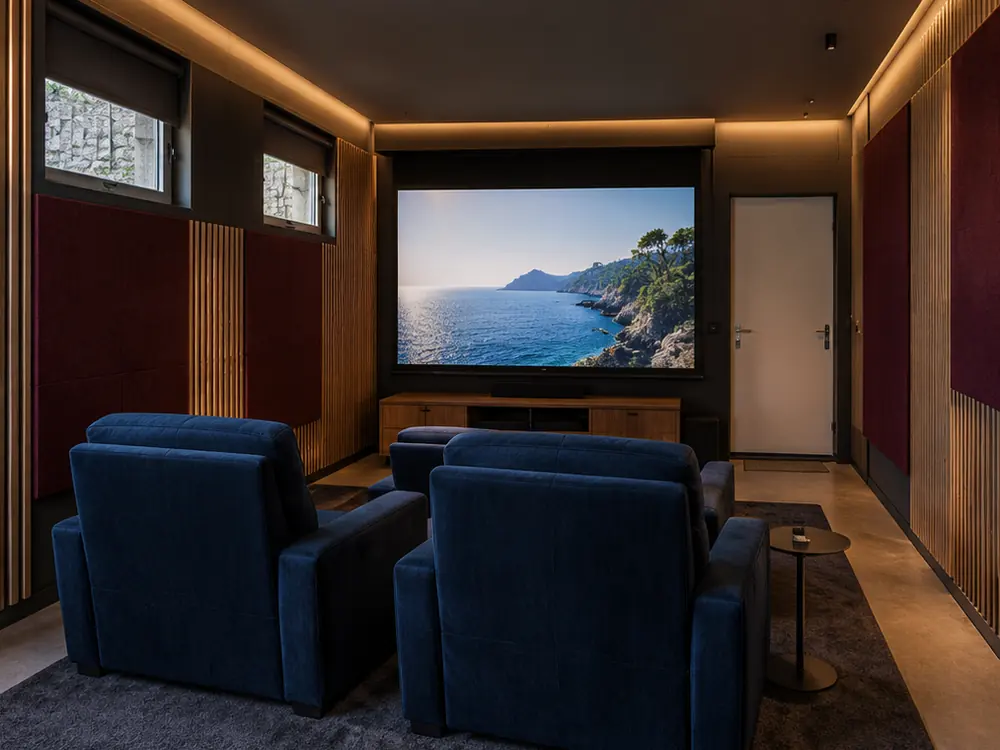 Simulation après travaux : le garage devenu salle de cinéma, fauteuils, écran et traitement acoustique